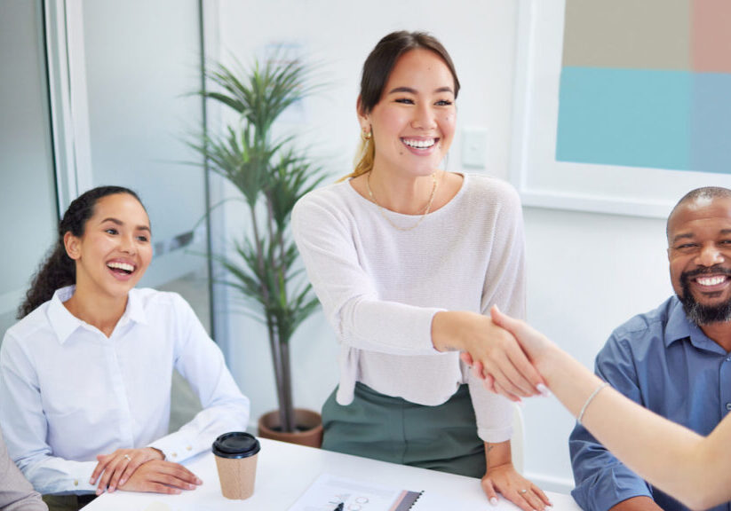 Business people, handshake and finance meeting in team for promotion, onboarding or welcome to company. Asian woman, shaking hands or happy for congratulations, hiring or thank you with deal in group.