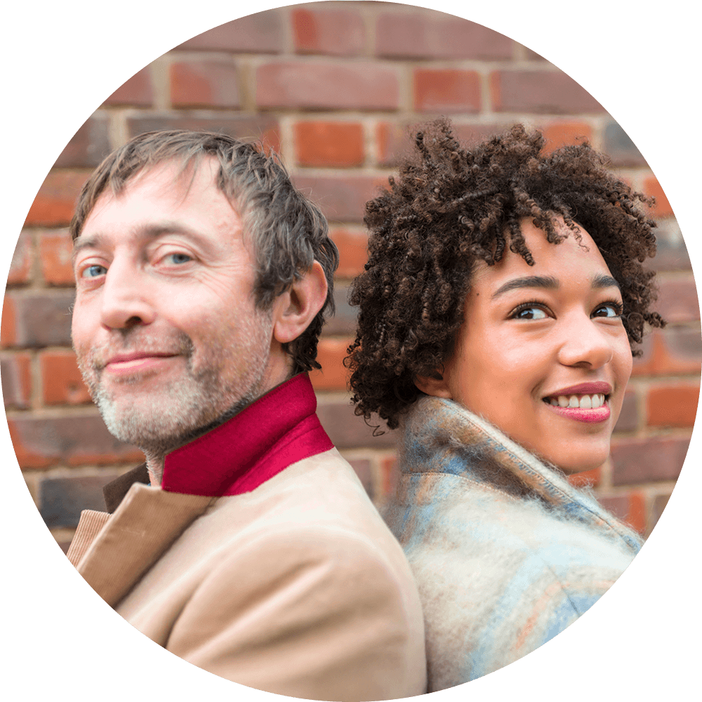 Image of two smiling people with their backs against each other.